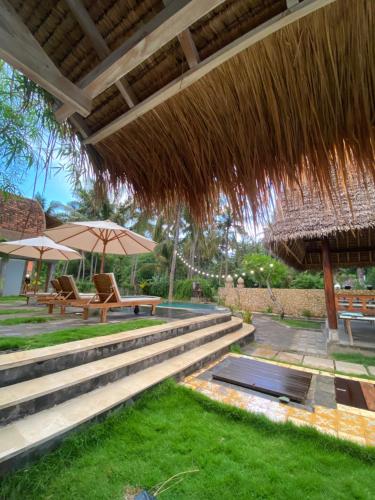 a patio with benches and umbrellas on the grass at Tentacle Bali in Nusa Penida