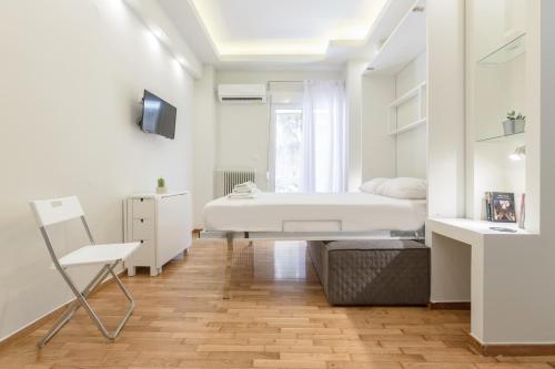a white bedroom with a bed and a chair at Cozy Flat with Terrace & Patio, next to Lycabettus in Athens