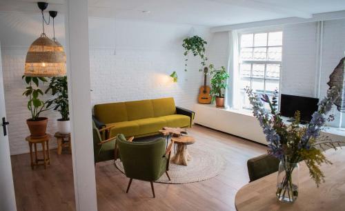 een woonkamer met een gele bank en een tafel bij Jantjes lief appartement in Zwolle