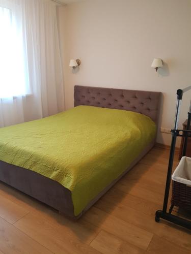 een slaapkamer met een bed met een groene sprei bij Neringa apartments in Klaipėda