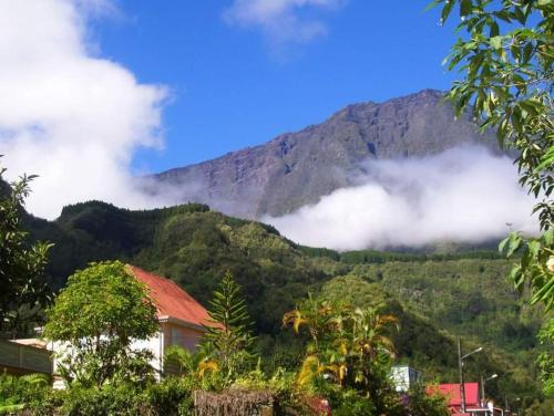 a mountain obscured by clouds with a house in the foreground at Au chant du coq in Salazie