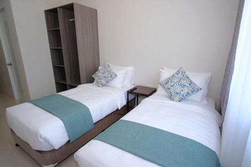 twee bedden in een kleine kamer met bij Sukro in Bacolod