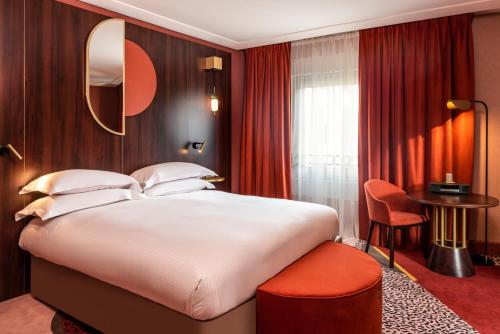 a hotel room with a large bed and a table at Nest Hotel Paris la Défense - MGallery Collection in Puteaux