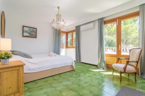a bedroom with a bed and a chair and a chandelier at S'Olivaret -Alcudia- in Port d'Alcudia