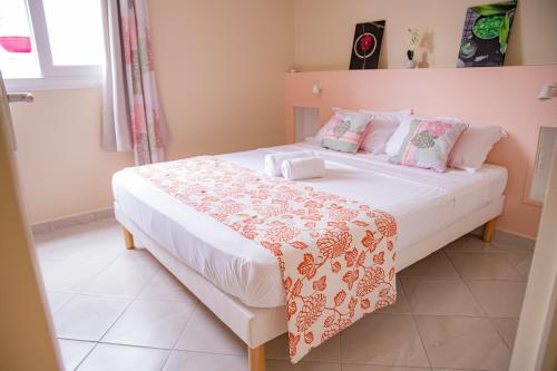 a bedroom with a large white bed with pink pillows at Villas Ixora in Sainte-Anne