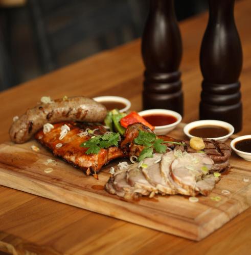 a plate of food with meat and sausages on a table at Ossotel Legian in Legian