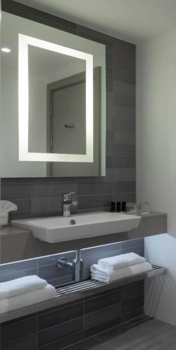 a bathroom with a sink and a mirror and towels at Clayton Hotel Charlemont in Dublin