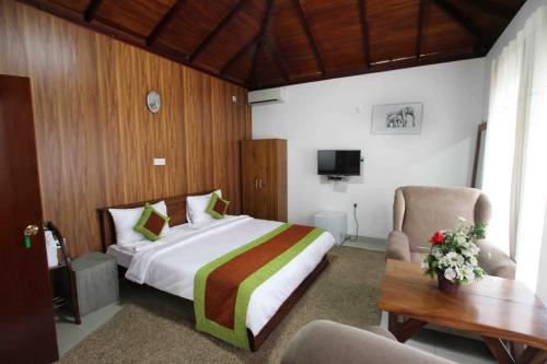 a bedroom with a bed and a table and a chair at Kandy Dawson Bungalow in Kadugannawa