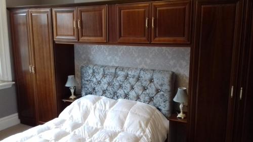 a bedroom with a bed and wooden cabinets at Lansdown House Bed & Breakfast in Market Drayton