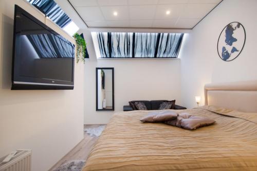 a bedroom with a large bed and a flat screen tv at Luxurious two bedroom apartment A kwartier Center in Groningen