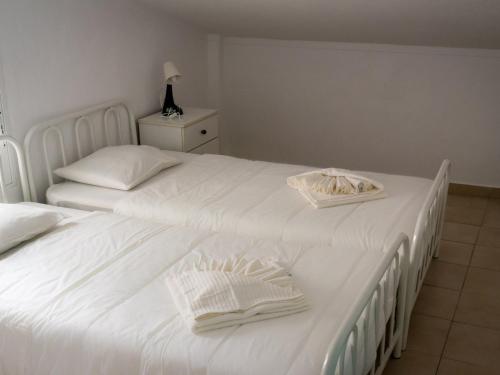 2 Betten in einem Schlafzimmer mit weißer Bettwäsche und Kissen in der Unterkunft Leisure Moments Maisonette by TravelPro Services Possidi Halkidiki in Posidi