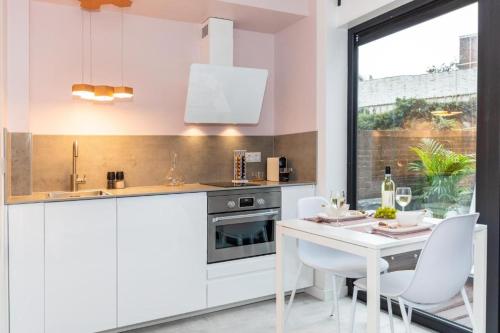 a kitchen with white cabinets and a white table and chairs at 2 rooms Sea Breeze loft apartment II terrace family Scheveningen The Hague in Scheveningen