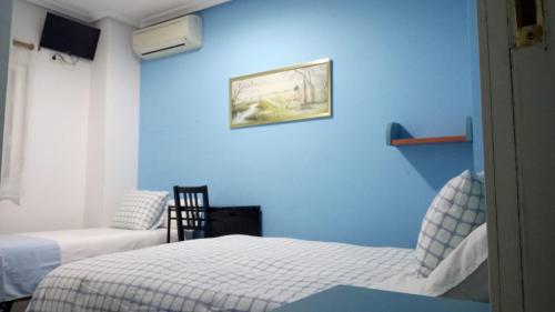 1 Schlafzimmer mit blauen Wänden und 2 Betten in der Unterkunft Pensión Navarra in Madrid