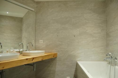 y baño con 2 lavabos, bañera y espejo. en Chalet Obelix, en Grindelwald
