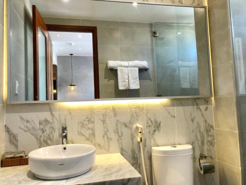 a bathroom with a sink and a mirror and a toilet at Coconut Hotel Phú Yên in Tuy Hoa