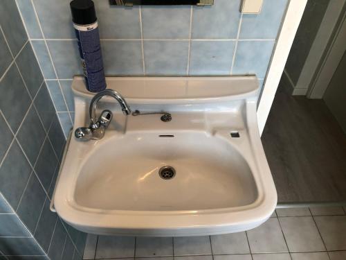 a white sink in a bathroom with blue tiles at Hôtel Belair "Ravel Etape" in Waimes