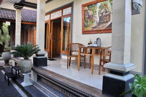um alpendre com uma mesa e cadeiras numa casa em Dunung Sari Homestay em Ubud