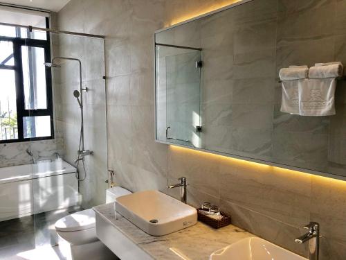 uma casa de banho com um lavatório, um WC e um espelho. em Coconut Hotel Phú Yên em Tuy Hoa