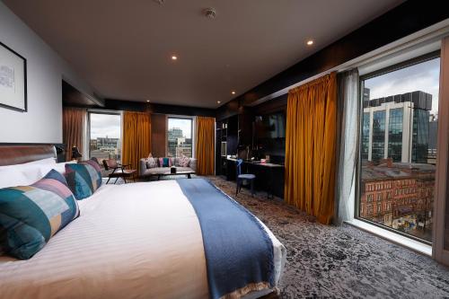 um quarto de hotel com uma cama grande e janelas grandes em voco Manchester - City Centre, an IHG Hotel em Manchester