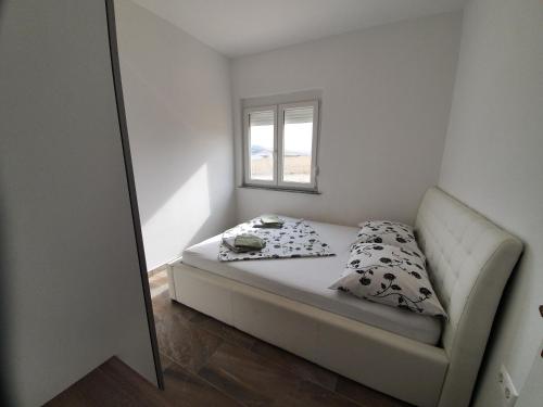 a small bedroom with a bed and a window at Amazing sea view apartments Ljubic in Pag