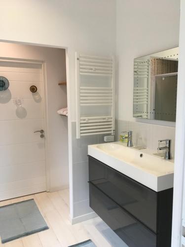 a white bathroom with a sink and a mirror at MADILOJE in Saint-Hilaire-de-Riez