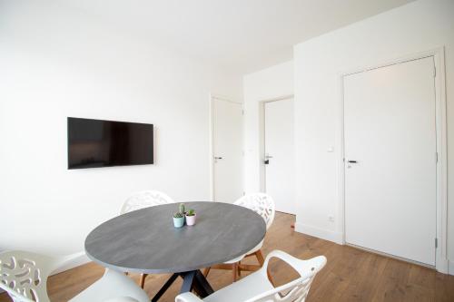 a dining room with a table and white chairs at Escamp Apartments in The Hague