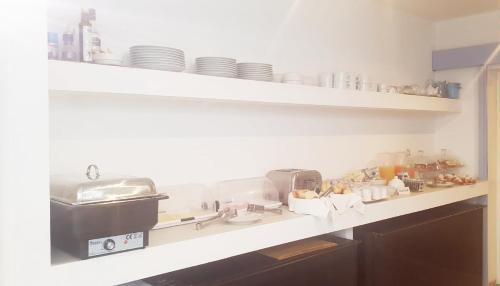 a kitchen with a counter with dishes on shelves at Hotel Intorno Al Fico in Fiumicino