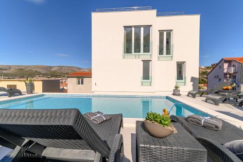 een villa met een zwembad en tuinmeubilair bij Villa Amazing View in Trogir