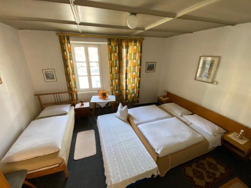 um quarto com 3 camas e uma janela em Gasthof Albergo Ressmair em Merano