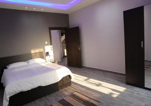 sypialnia z dużym łóżkiem i niebieskim światłem w obiekcie Dar Gerasa chalets The THREE Palm w mieście Dżarasz