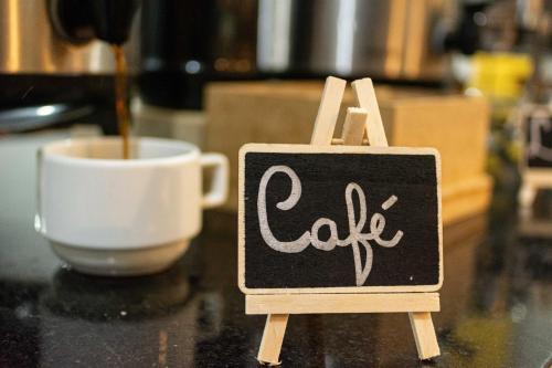 a chalkboard sign on a table next to a cup of coffee at Abudi Hotel in Cuiabá
