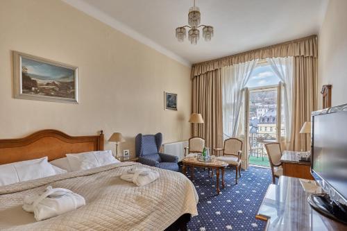 カルロヴィ・ヴァリにあるHotel Romanceのベッドとテレビが備わるホテルルームです。