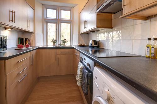 uma cozinha com armários de madeira e um balcão preto em Bridge House By Treetop Property em Cirencester
