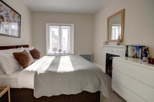 a white bedroom with a bed and a fireplace at Bridge House By Treetop Property in Cirencester