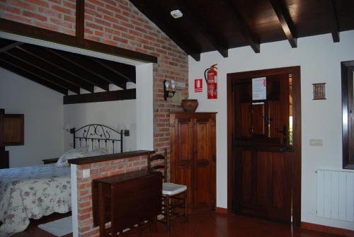 sypialnia z łóżkiem i ceglaną ścianą w obiekcie Apartamentos El Perujo w mieście Comillas