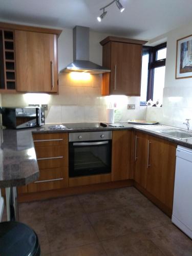 a kitchen with wooden cabinets and a stove top oven at Ivydene Cottage in Mablethorpe