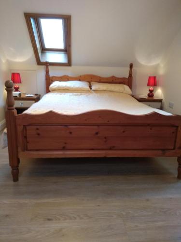 een slaapkamer met een groot houten bed met 2 lampen bij Ivydene Cottage in Mablethorpe