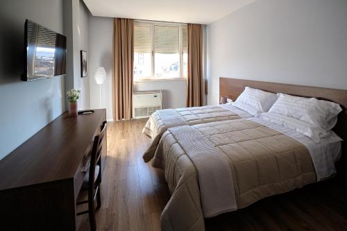 a bedroom with a bed and a dresser and a desk at In Center Hotel in Tirana