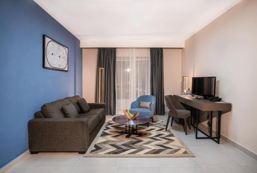a living room with a couch a table and a desk at Hotel Holiday International in Sharjah