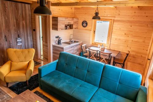 Happy2cu Cabin في كولاسين: غرفة معيشة مع أريكة زرقاء ومطبخ
