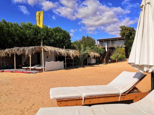 a beach chair and an umbrella and a building at The Wind Farm in Dahab