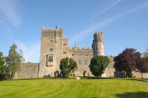 a castle with two towers on a green field at Kilkea Castle in Kilkea