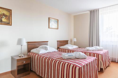 two beds in a hotel room with towels on them at BURSZTYN - BERNSTEIN SPA & Wellness in Dąbki
