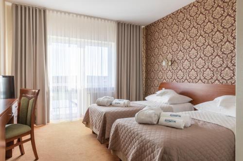ein Hotelzimmer mit 2 Betten, einem Schreibtisch und einem Fenster in der Unterkunft BURSZTYN - BERNSTEIN SPA & Wellness in Dąbki