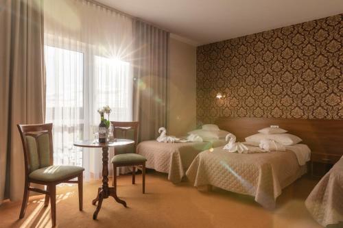 a hotel room with two beds and a table and chairs at BURSZTYN - BERNSTEIN SPA & Wellness in Dąbki