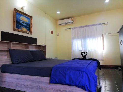 a bedroom with a bed with blue sheets and a window at Phurafa Resort in Phang-nga