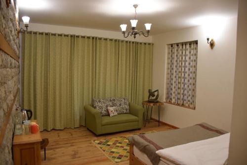 a bedroom with a green chair and a couch at Kudrat - A Boutique Homestay- Tirthan Valley in Banjār