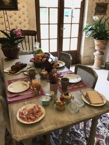 une table en bois avec des assiettes de nourriture dessus dans l'établissement la VILLA B Chantilly, à Orry-la-Ville