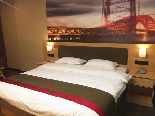 a bedroom with a large bed with a painting on the wall at Thank Inn Chain Hotel guangxi liuzhou luzhai county square in Liuzhou