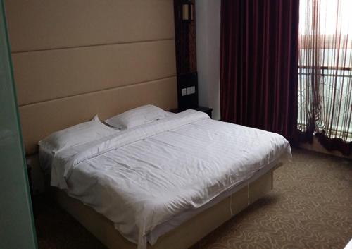 Una cama con sábanas blancas y almohadas en un dormitorio en Thank Inn Chain Hotel Shandong Qingdao huangdao chongming island road, en Qingdao